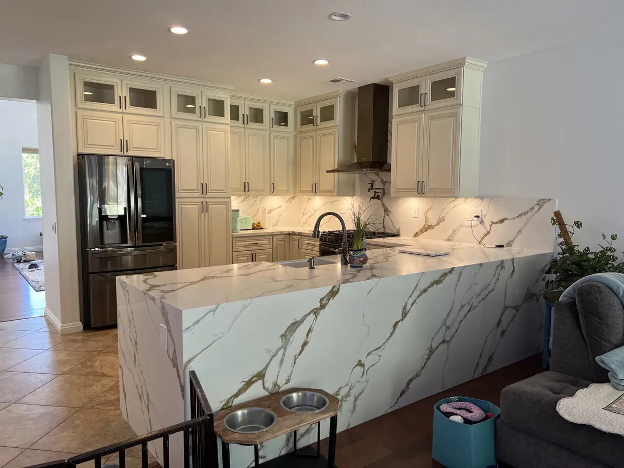 Finished kitchen with cream cabinets and marble waterfall island by Safeway Construction