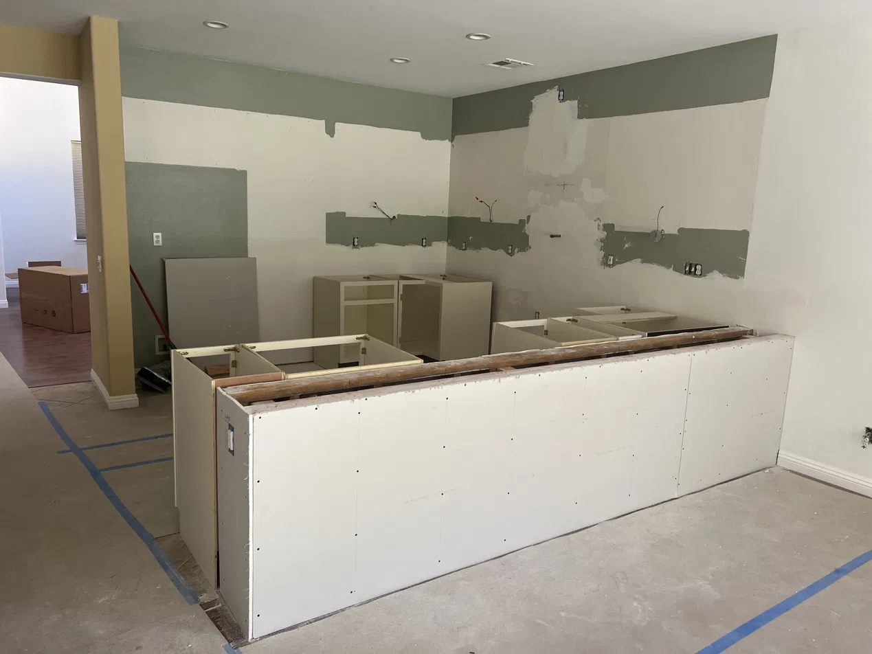 Kitchen mid-demolition, cabinets removed and walls prepped
